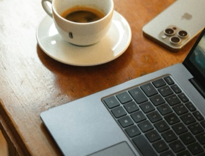 Writing setup: espresso, phone, and laptop on a wooden desk